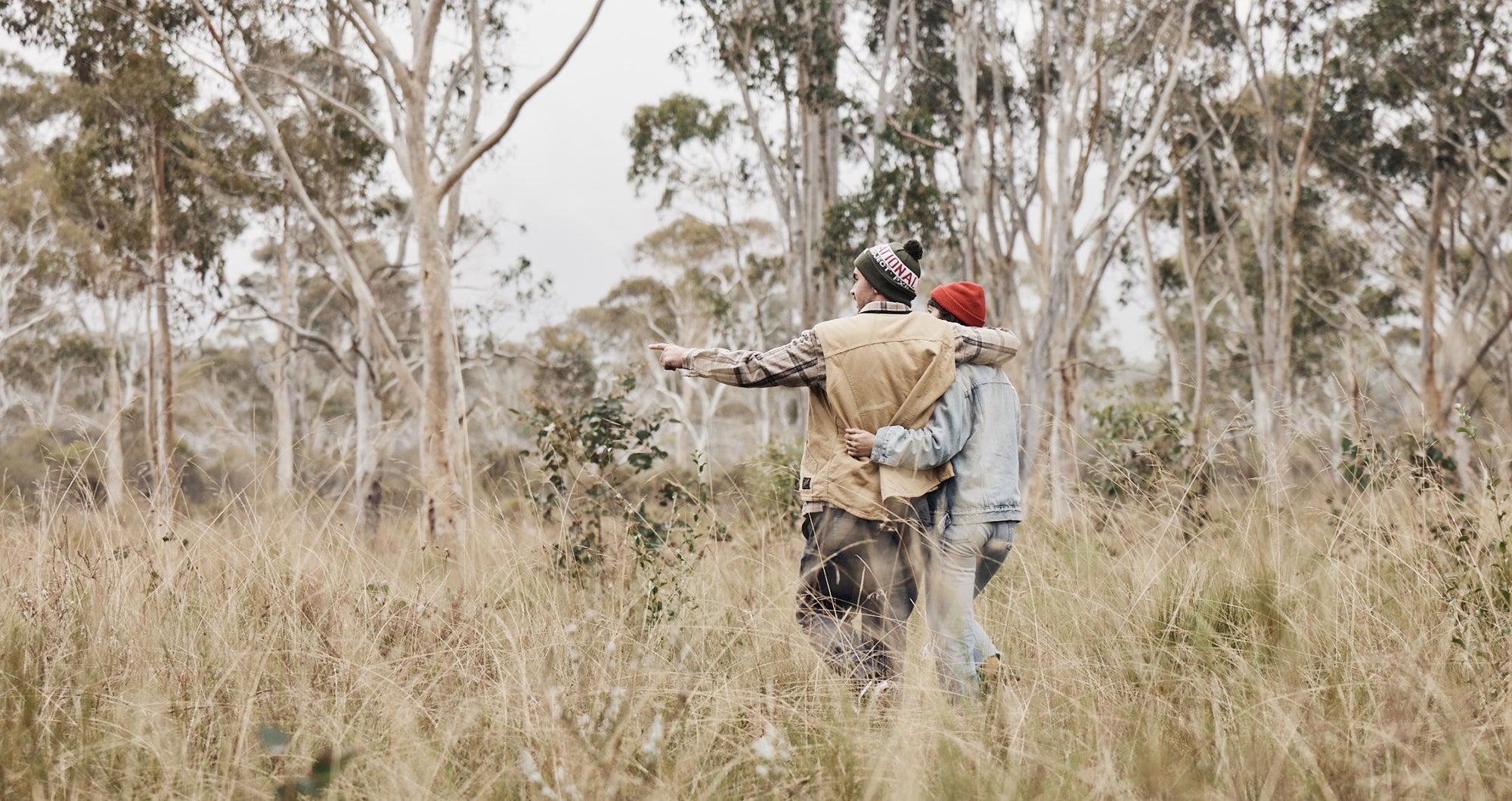couple walking in grassland arm in arm with winter hiking hear on